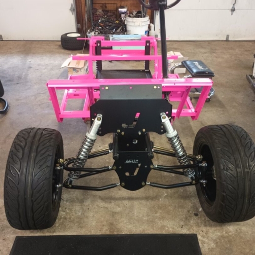 Custom golf cart frame with pink powder coating and suspension components.