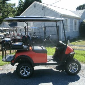 Customized red and black golf cart with aftermarket wheels and accessories.