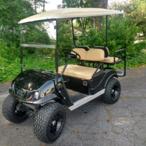 Customized black and beige golf cart with premium wheels and accessories.