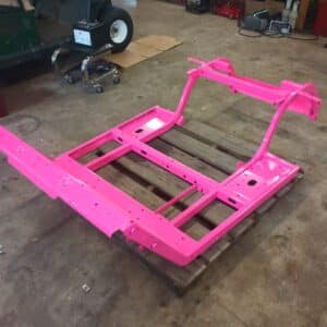 Custom golf cart frame transformation, pink painted chassis on pallet.