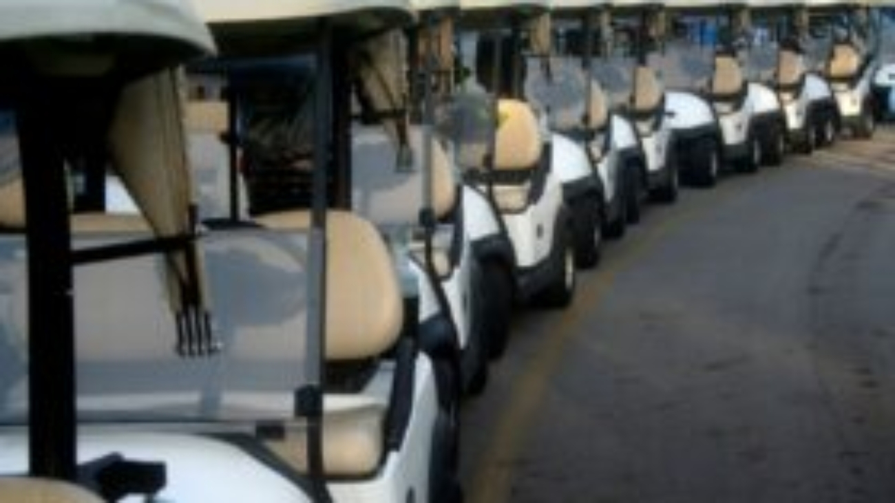 Row of white golf carts awaiting customization at Flamingo Custom Carts
